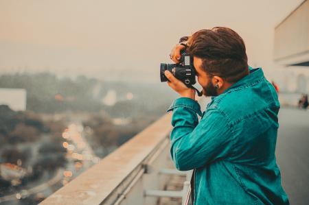 Man In Teal Button-Up Long Sleeved Shirt Shooting Using DSLR Camera