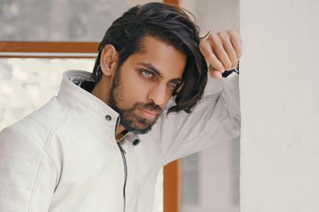 Man in White Zip-up Jacket Leaning on White Painted Wall