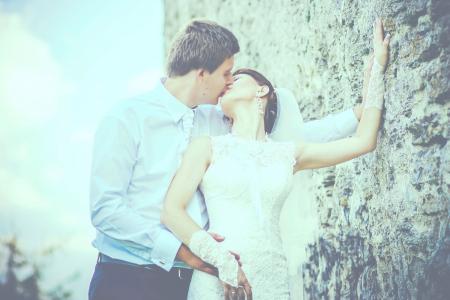 Man Kissing Woman Wearing Sleeveless Wedding Gown