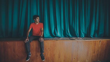 Man on Red Crew-neck T-shirt Sitting on Stage