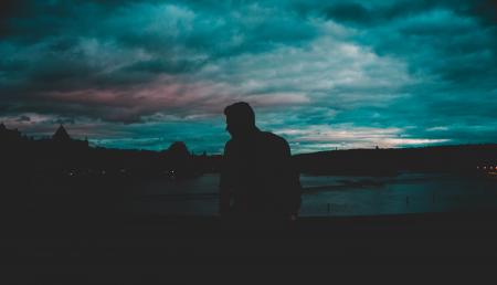 Man Silhouette Near Body of Water at Nighttime