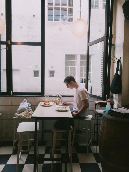 Man Sitting in Front of Table Holding Smartphone Beside Window