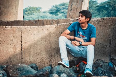 Man Sitting on Stone Leaning on Concrete Wall