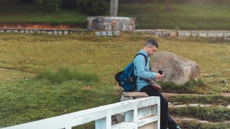 Man Sitting on White Railing Near Rock