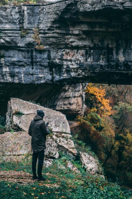 Man Standing in Front of Rock Formation