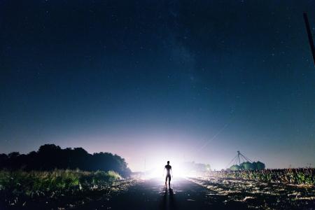 Man Standing on the Road Near Green Grass during Sunrise
