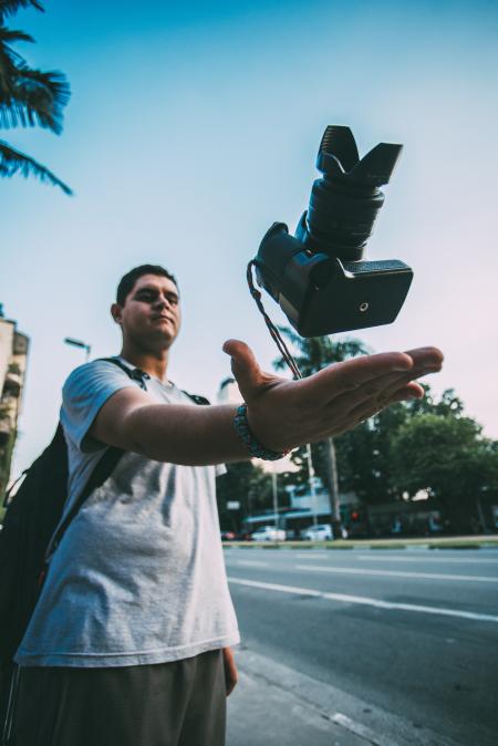 Man Throwing Black Camera in Air