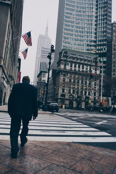 Man Walking on Road Wearing Suit Jacket and Dress Pants Beside High-rise Concrete Buildings