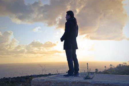 Man Wearing Black Coat Standing Near Sea during Golden Hour