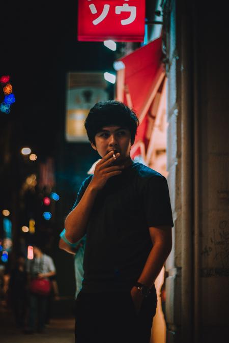 Man Wearing Black Crew-neck Shirt Holding White Cigarette during Night Time