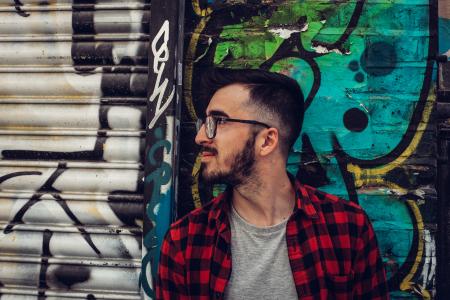 Man Wearing Black Framed Eyeglasses Standing Beside Blue and Black Wall