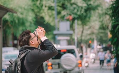 Man Wearing Black Hoodie Holding Dslr Camera Shooting on Upper Direction