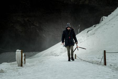 Man Wearing Black Jacket Brown Jeans and Black Shoes Walking on Snow