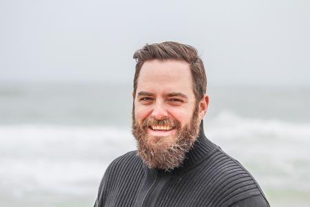 Man Wearing Black Zip-up Jacket Near Beach Smiling at the Photo