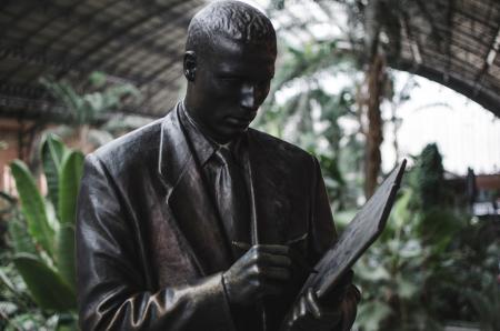 Man Wearing Blazer Holding Book and Pen Statue