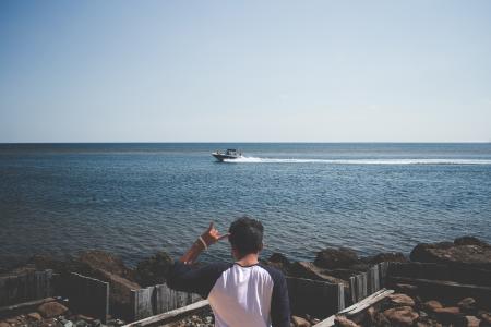 Man Wearing Blue and White T Shirt Next to a Seashore