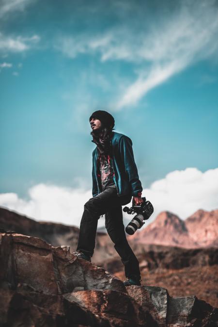 Man Wearing Blue Jacket Holding a White and Black Dslr Camera