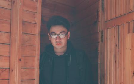 Man Wearing Eyeglasses and Hoodie Jacket in Wooden Room