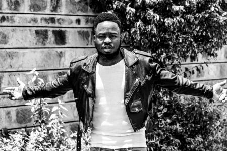 Man Wearing Leather Jacket Standing Near Concrete Wall Beside Plants