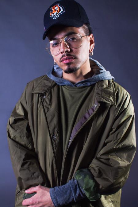 Man Wearing Olive Green and Black Collared Jacket Standing in Front of Black Background