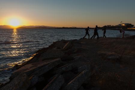 Men dancing on rocky outcrop in front of setting sun