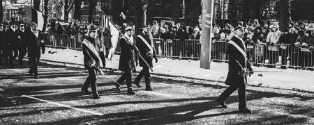 Men Walking on Streets Carrying Flag during Parade In Grayscale Photo