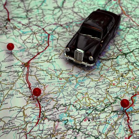 Miniature car and pushpins on a map - Travel concept