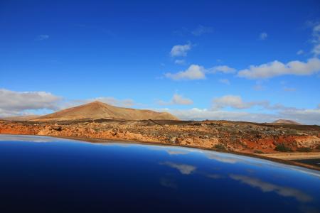 Mountain Beside Body of Water Under Cloudy Sky