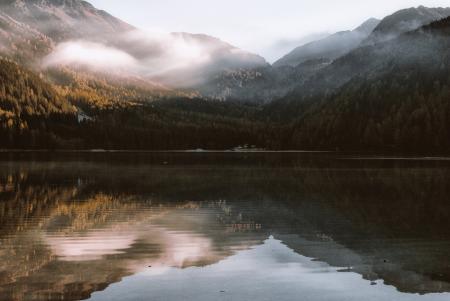 Mountain Reflection on Body of Water Under White Sky at