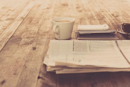 Newspaper and White Ceramic Cup on Brown Wooden Table