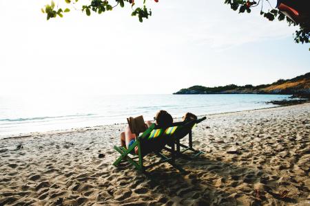 People Lying On Green Wooden Lounger Chairs On Beach