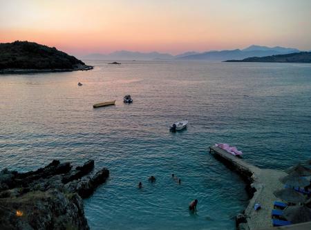 People Swimming in Sea Near Mountain Rocks