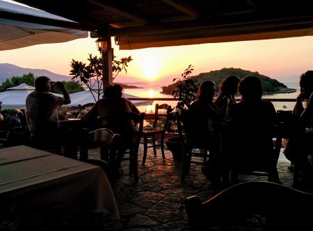 People Under Shed Watch Sunset Along the Island