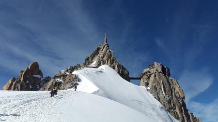 People Walking Toward Top of Mountain on Snow Covered Ground during Daytime