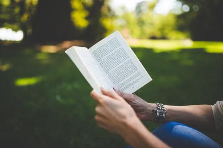 Person Holding and Reading Book during Daytime