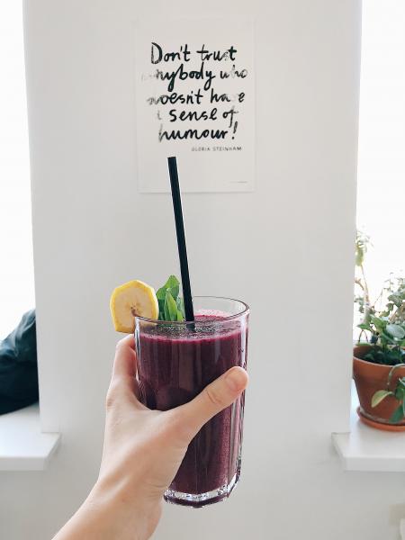 Person Holding Clear Drinking Glass With Purple Smoothie With Quotation Decor