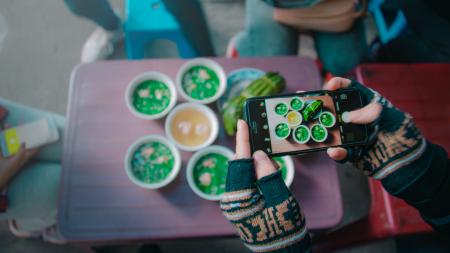 Person Holds Black Iphone Taking Photo of Round White Ceramic Bowl