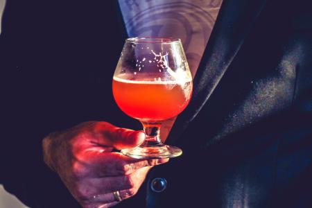 Person Holds Clear Glass Snifter With Red Beverage