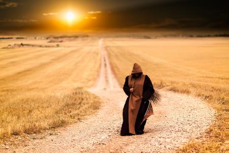 Person in Brown and Black Robe in the Middle of the Road