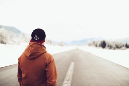 Person in Brown Hoodie Standing on Asphalt Road