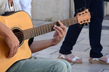 Person in Grey Shirt and Blue Denim Jeans Playing Acoustic Guitar
