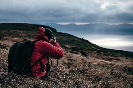 Person in Red Hoodie Taking a Photo of Wilderness