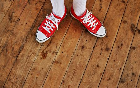 Person in Red Low Tops in Brown Wooden Floor