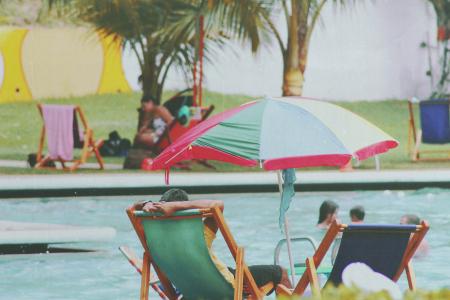 Person Lying on Bench Near Swimming Pool