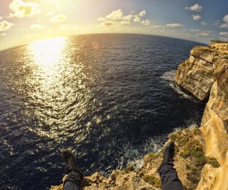 Person on Top of Stone Island in Front of Sea during Sunset