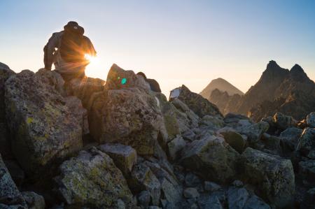 Person Sitting on Gray Rocks Under Clear Blue Sky