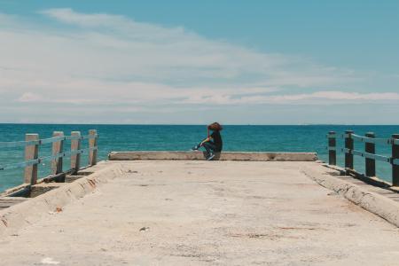 Person Sitting on the Edge of the Beach Dock