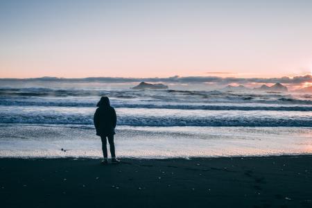 Person Standing on Beach Seashore during Sunset