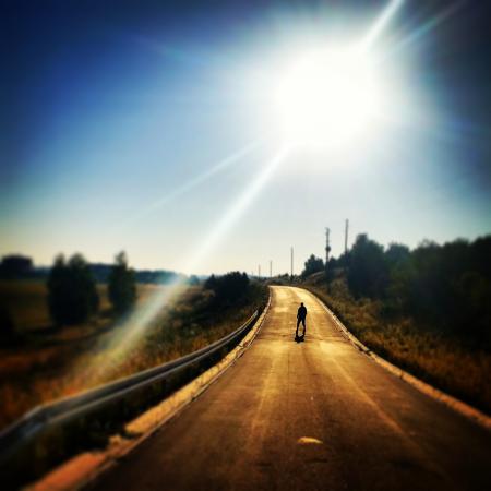 Person Standing on Blacktop Road Under Blue Sky During Daytime