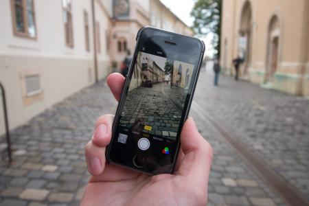 Person Taking a Photo of Empty Black and Gray Concrete Road Between Beige Paint Wall Concrete Building